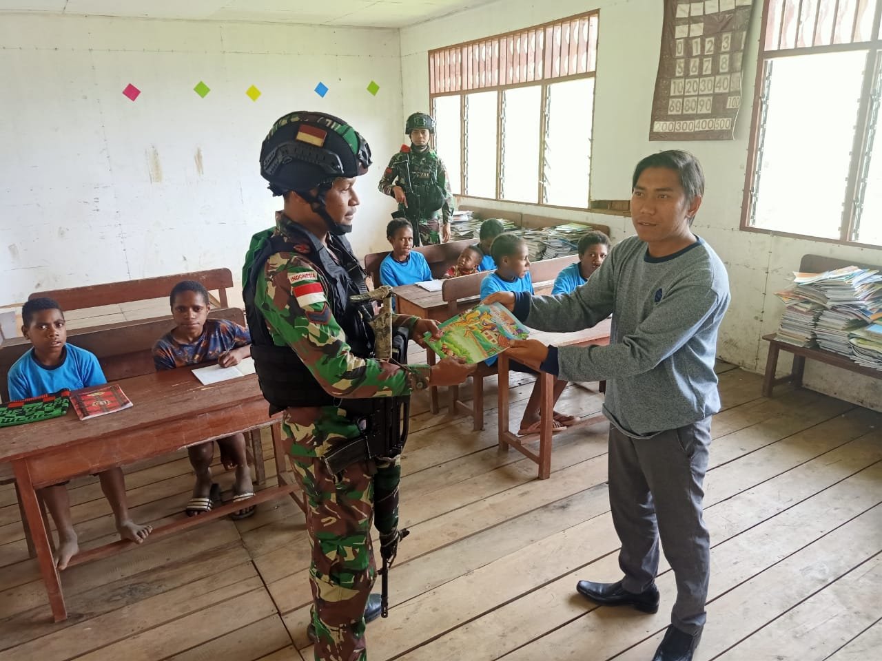 Personel Satgas Kodim Yalimo Yonif RK 751/VJS Bagikan Buku Bergambar untuk Anak-Anak